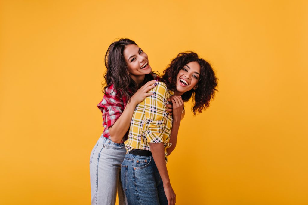 positive-girls-relax-have-fun-photo-shoot-yellow-room-portrait-laughing-tanned-girls-with-curly-hair